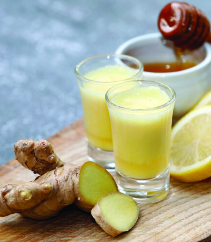 Ginger drink, shot, juice with healthy ingredients like ginger root, honey and lemon on wooden background.